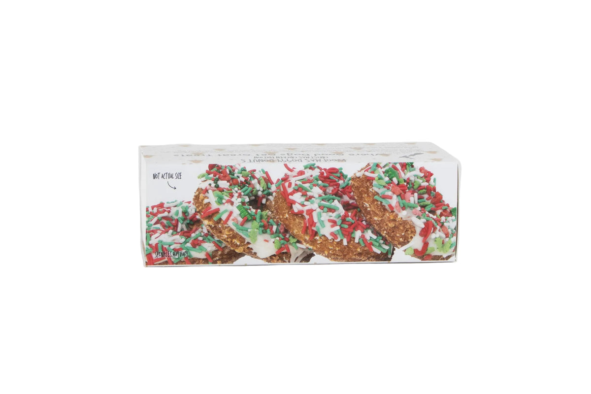 A rectangular box of holiday-themed donuts decorated with white icing and red and green sprinkles, shown on a plain white background.