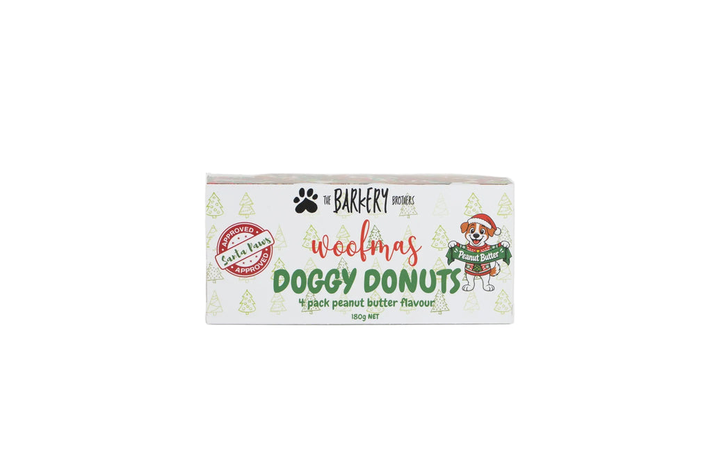 A rectangular box of 'The Barkfery Doggy Donut' Christmas themed dog treats, featuring a white background with green pine tree illustrations, red and green text, and a cartoon dog wearing a Santa hat and sweater.